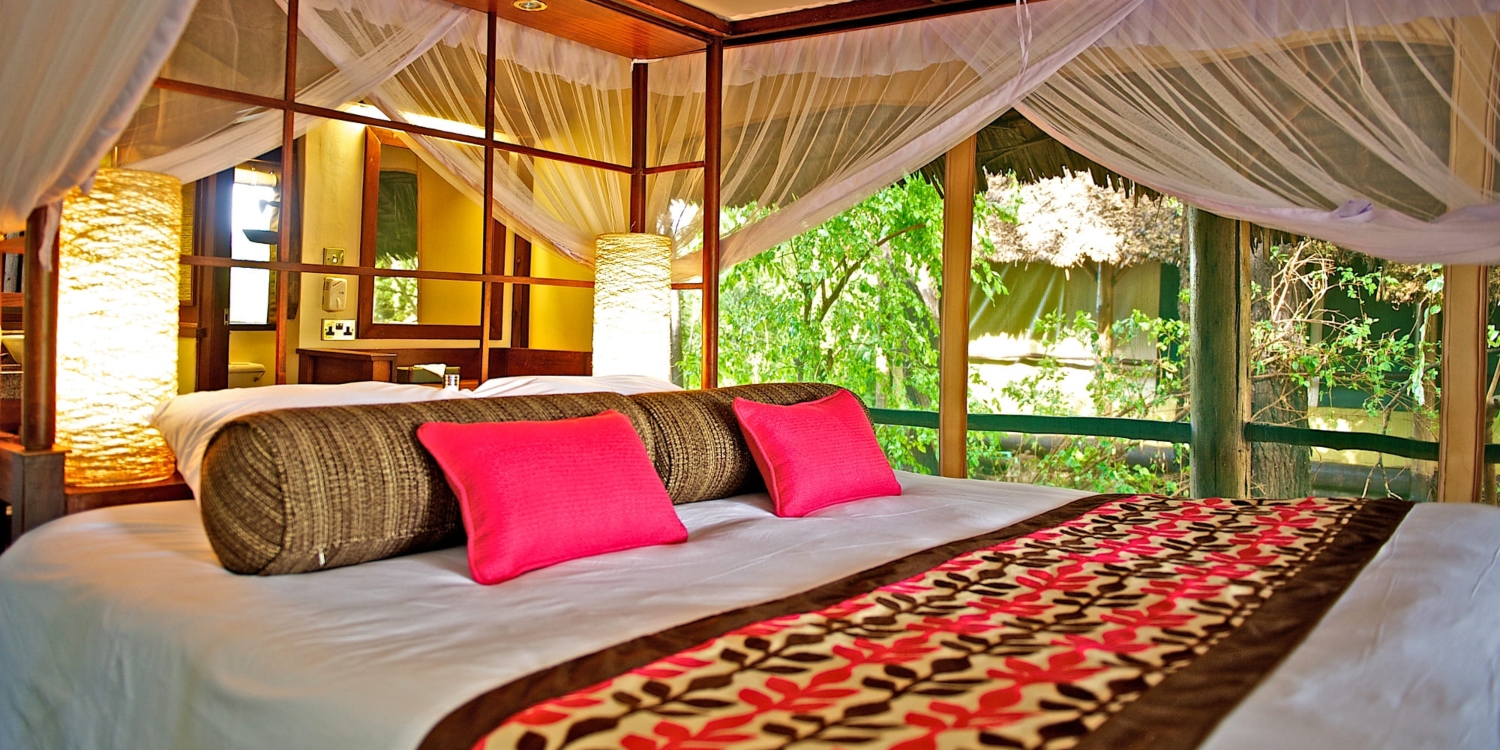 samburu-intrepids-camp-luxury-safari-kenya A scenic view of Samburu Intrepids Camp with luxury tents overlooking the Ewaso Nyiro River in Samburu National Reserve, Kenya.